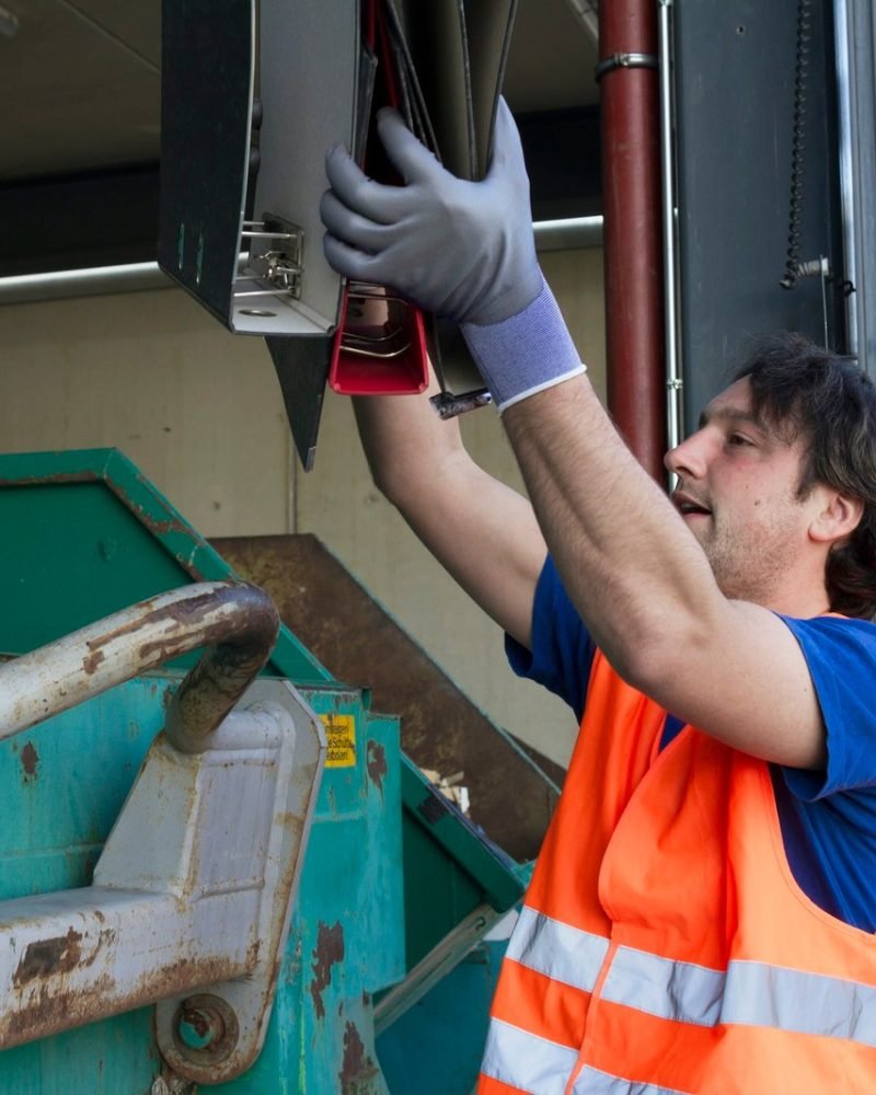 worker-at-a-waste-container-throwing-away-folders.jpg