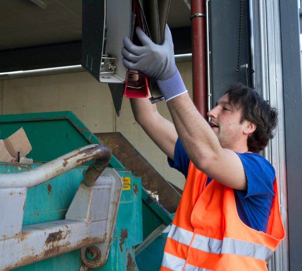 worker-at-a-waste-container-throwing-away-folders.jpg